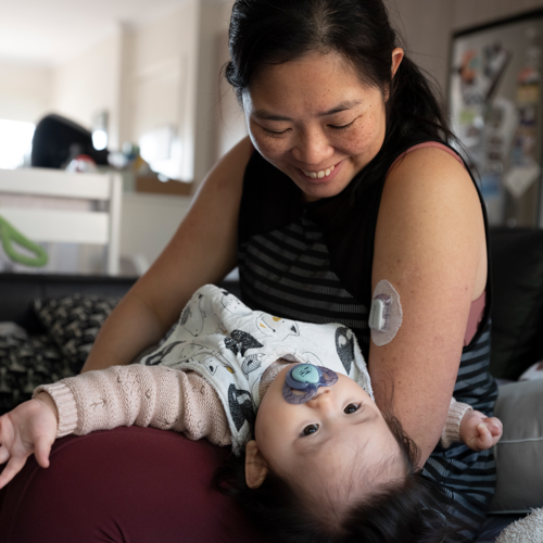 Femme asiatique tenant un jeune enfant et souriant.