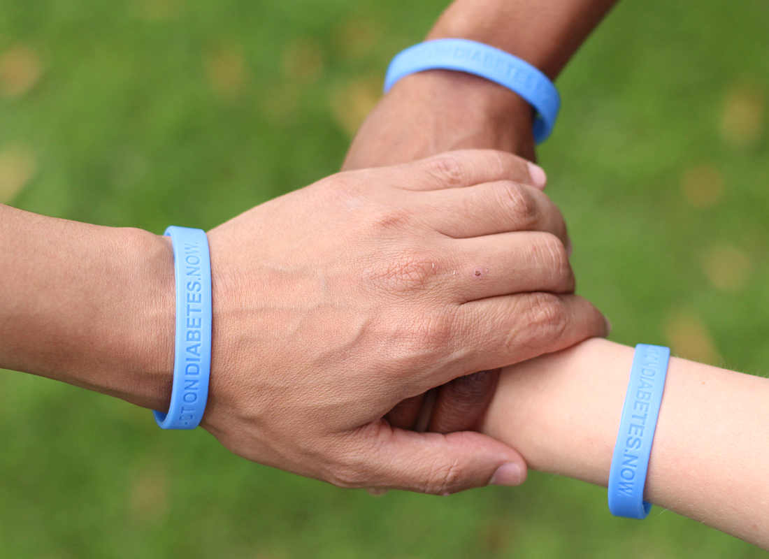tres manos cruzadas con pulseras azules