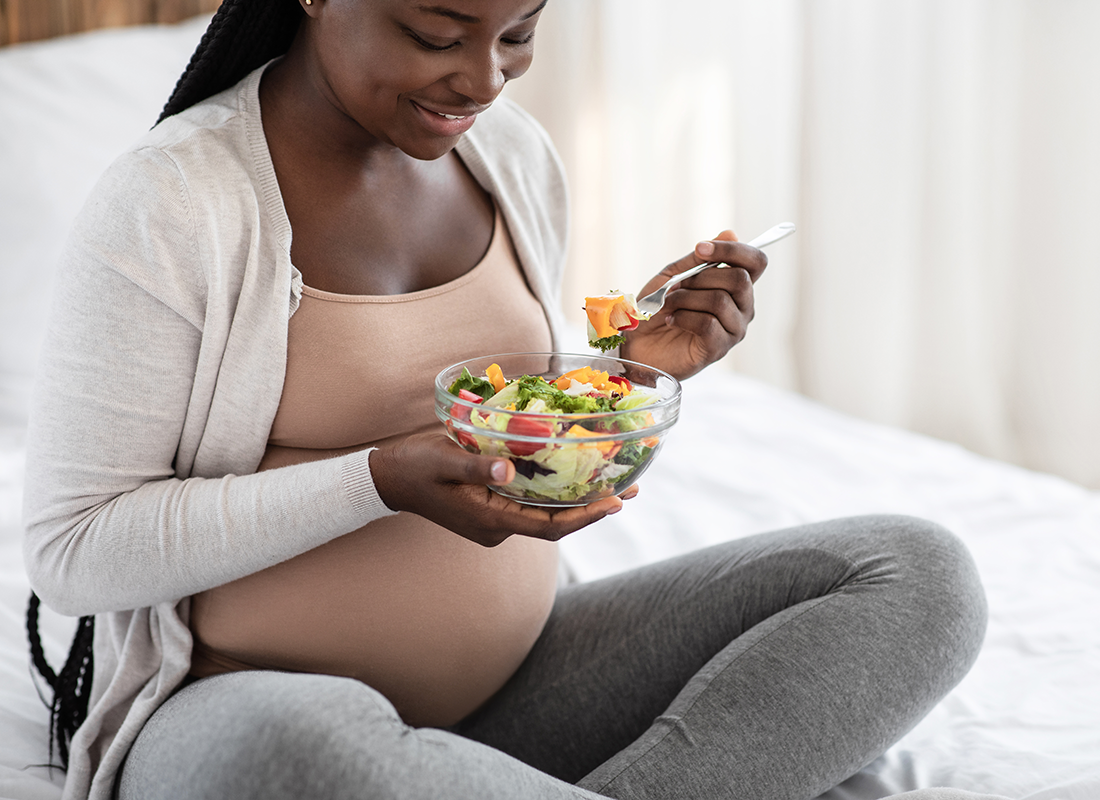 Pregnant woman of African origin eating a salad