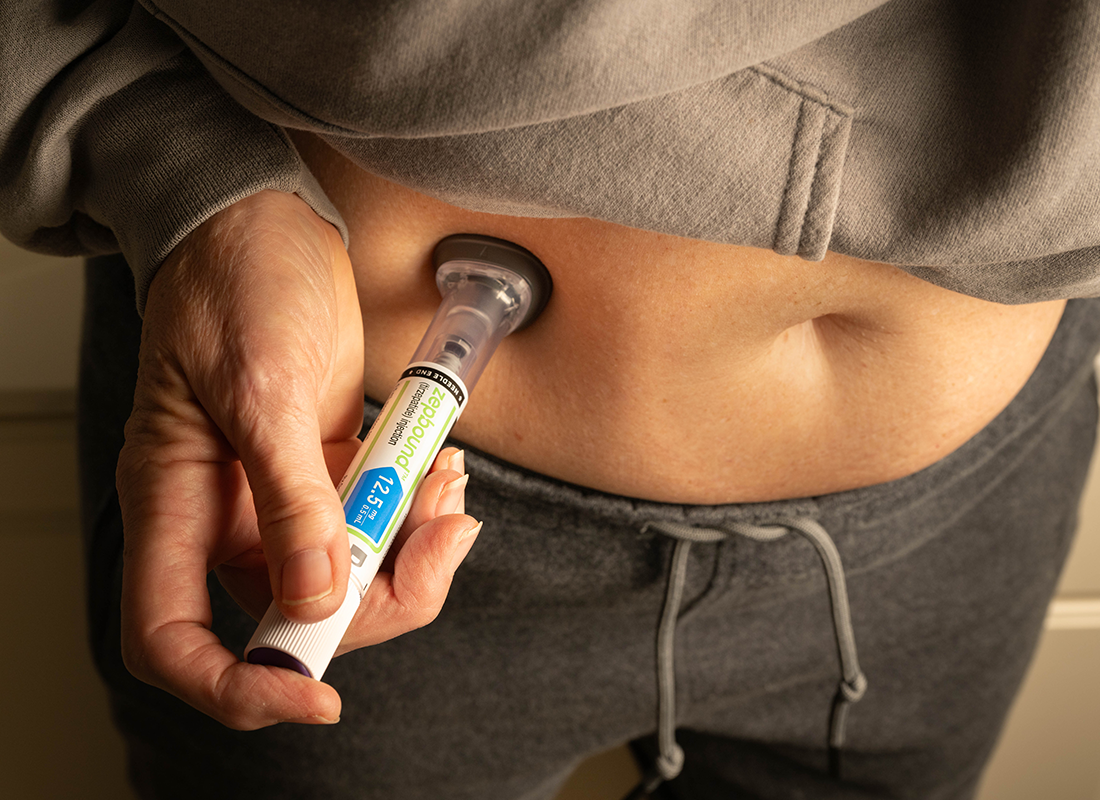 Une femme utilisant un stylo injecteur pour s'administrer du GLP-1 dans l'abdomen.