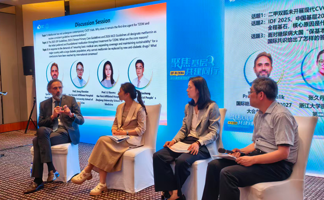 El profesor Rayaz Malik participa en una mesa redonda con expertos chinos en diabetes durante la gira de intercambio FID en China, con una pantalla de presentación al fondo.